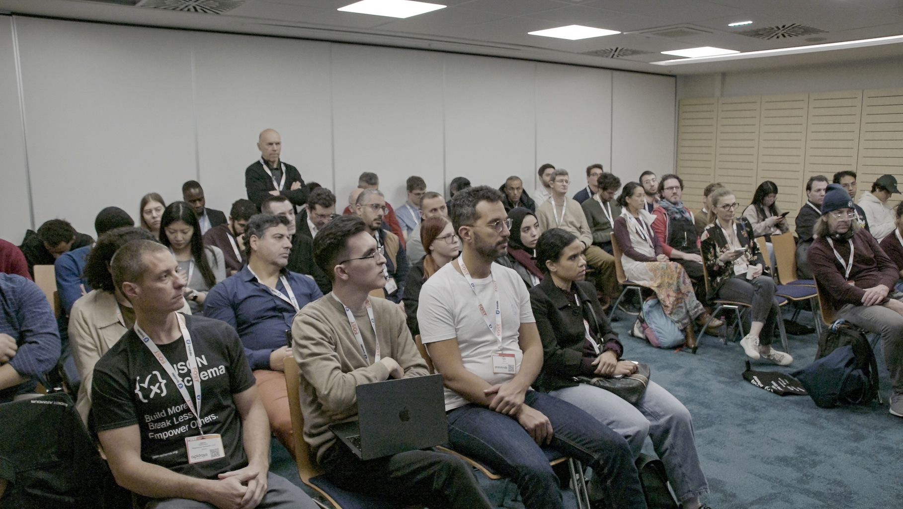 JSON schema conference room with attendees listening to a presentation. The image is taken from a front view and it is not showing the presenter in this picture.